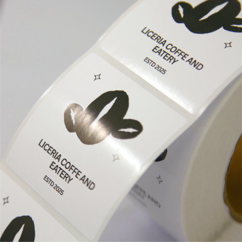 Black and white custom printed square sticker with a black graphic of coffee beans and text reading "Liceria coffee and eatery, ESTD 2025"