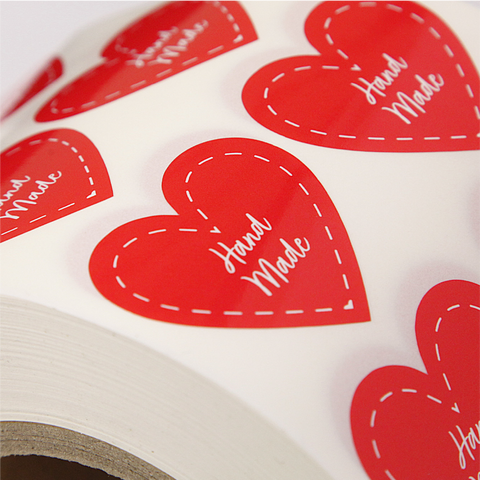 Bright red heart shaped custom stickers with a dotted white line heart and "Hand Made" written inside