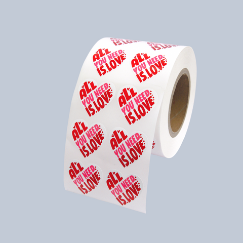 Roll of custom heart shaped stickers saying "All you need is love".