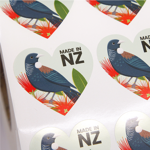 Heart shaped sticker with Tui and Pohutakawa flowers on a light green background and text "Made in NZ"