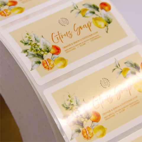 Close up of custom printed citrus soap rectangle sticker with lemon and orange illustrations on a beige background.